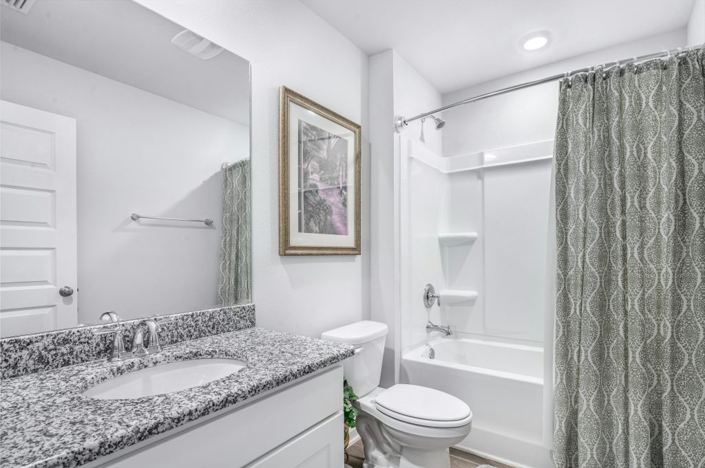 Bright and clean modern bathroom with granite countertop and elegant decor.